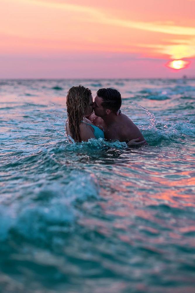 proposals kiss in a sea on a colorful sunglow