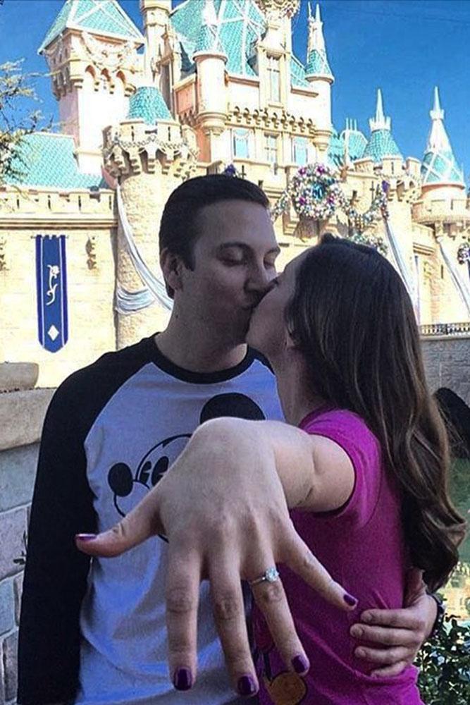 Disney proposals kiss on disney castle backgraund and engagement ring on her finger