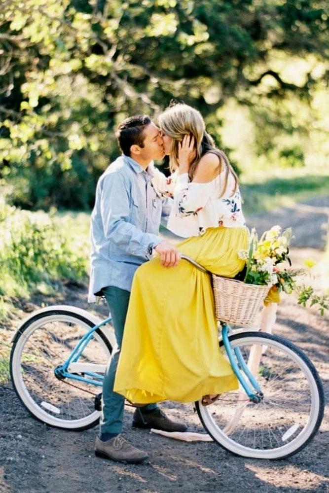 engagement photo ideas woman sits on bike man kisses her