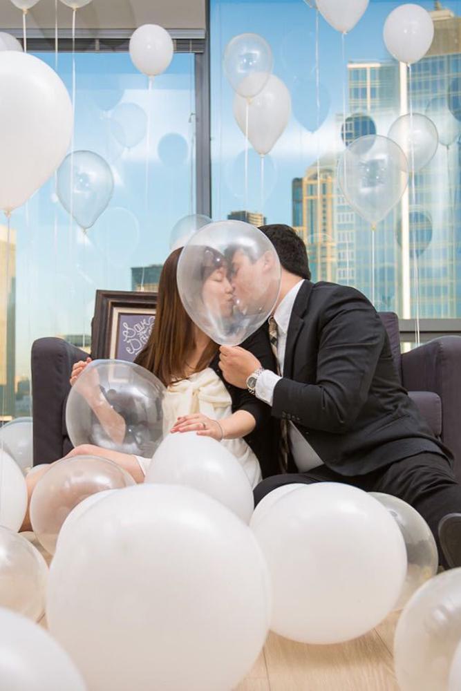 engagement pictures a kissing couple among white blowed ballons decoration