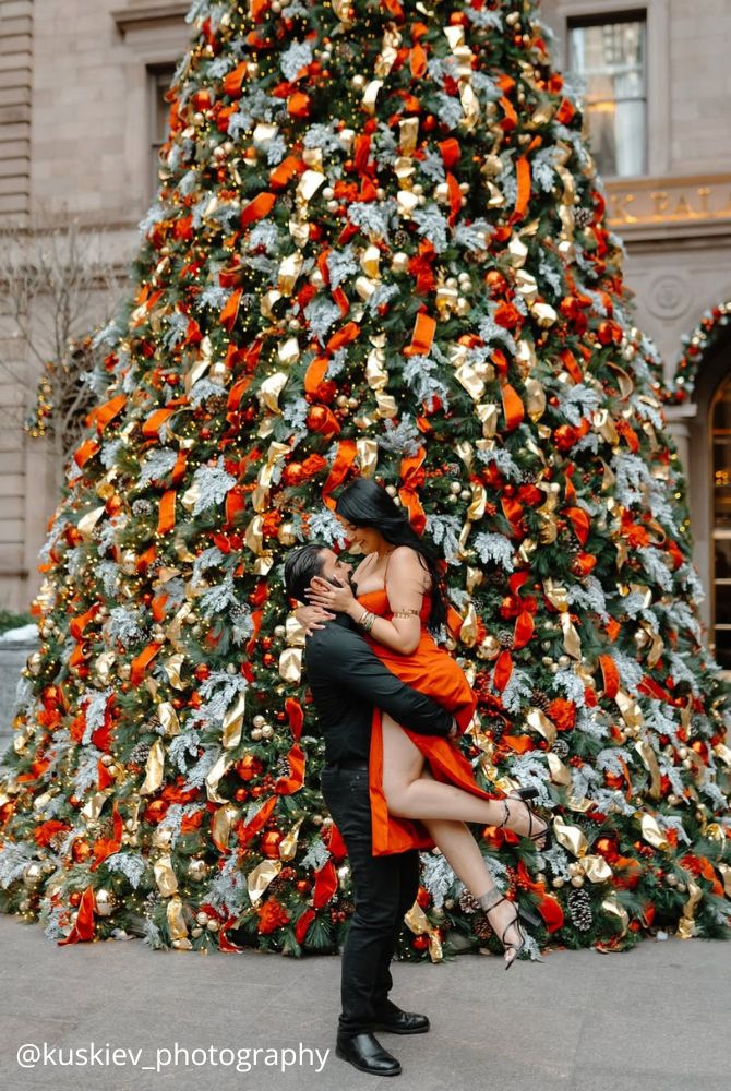 christmas proposal lovers in the city around the tree he holds her beautiful red dress kuskiev photography