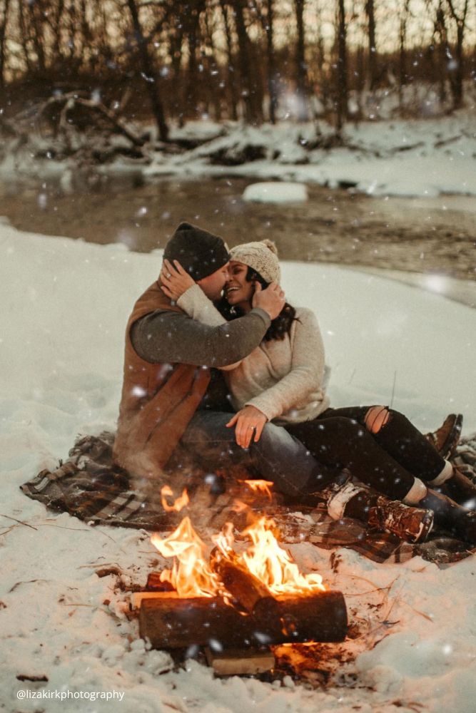 new year engagement photos a couple sitting next to a fire in the snow lizakirkphotography