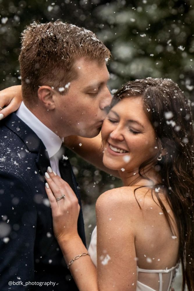 winter engagement photos boy kissing a girl in forehead falling snow bdfk photography