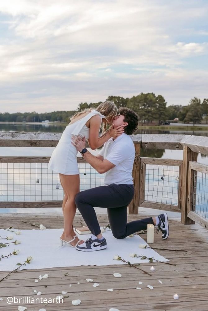 cheap proposal ideas couple kissing during lake dock proposal decorated with white rose petals brilliantearth