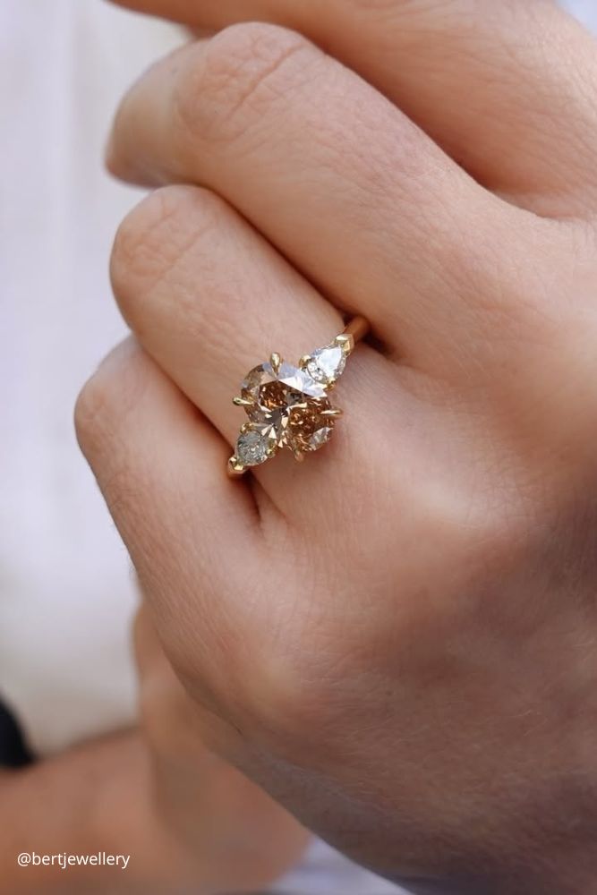 solitaire engagement rings ring on the finger of yellow gold with a stone in the center of an oval shape yellow stone bertjewellery