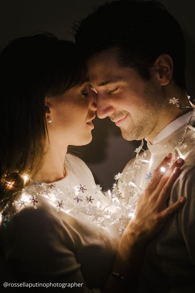 christmas proposal love couple wrapped in lighting garlands with eyes closed rossellaputinophotographer